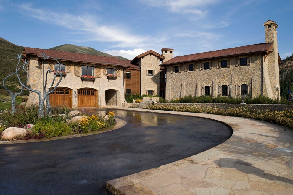Large mediterranean two-storey beige exterior in Denver with stone veneer, a gable roof and a red roof.