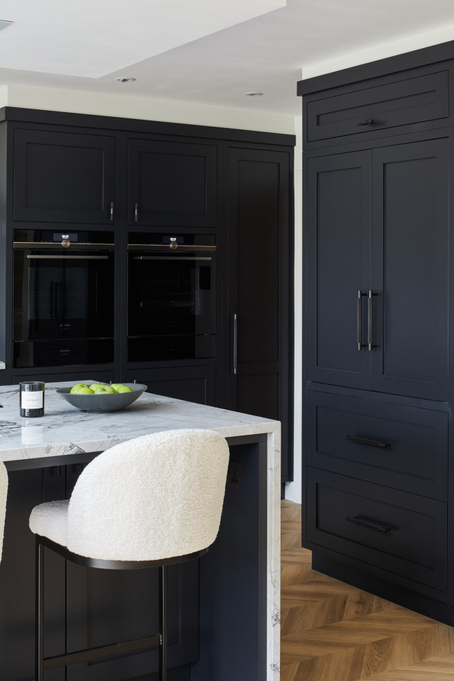 Inspiration for a large transitional l-shaped eat-in kitchen in London with recessed-panel cabinets, black cabinets and with island.