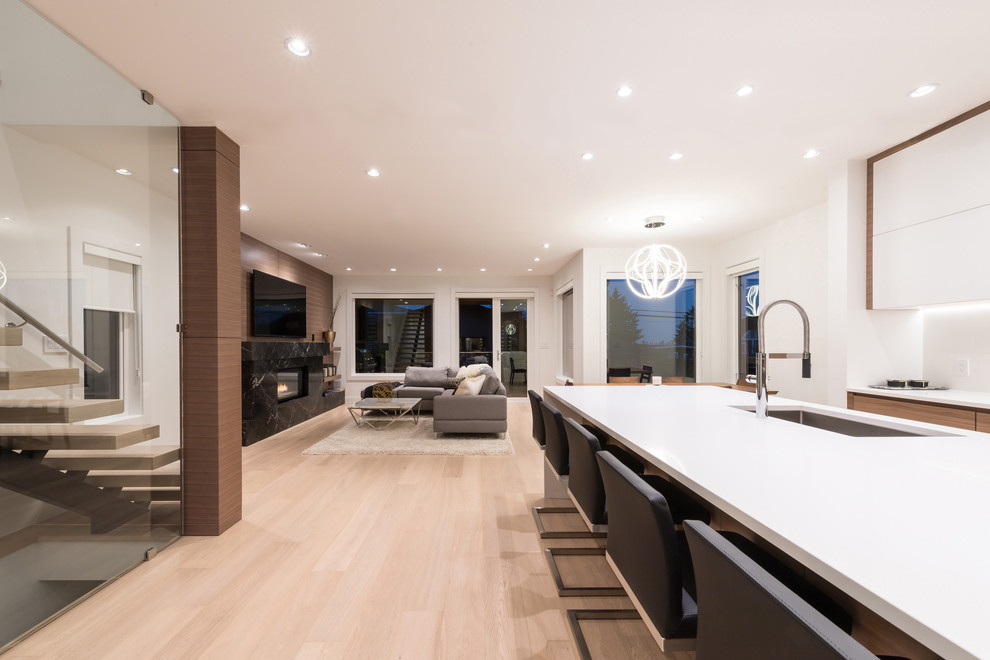 Inspiration for a mid-sized beach style l-shaped eat-in kitchen in Vancouver with an undermount sink, flat-panel cabinets, medium wood cabinets, quartz benchtops, white splashback, stone slab splashback, stainless steel appliances, light hardwood floors and with island.