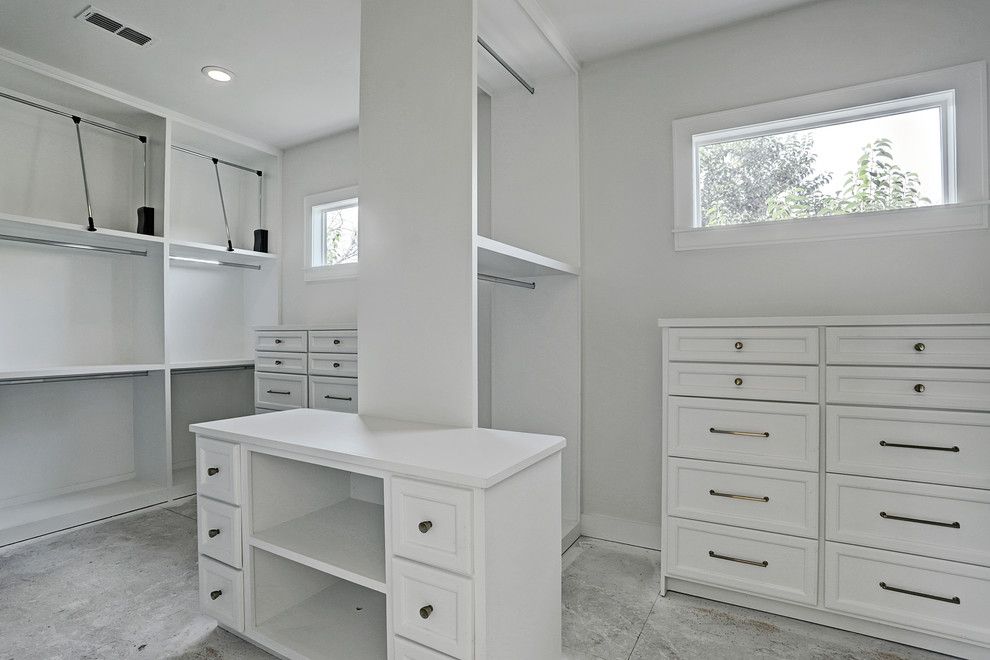 This is an example of a mid-sized contemporary gender-neutral dressing room in Houston with recessed-panel cabinets, white cabinets and concrete floors.