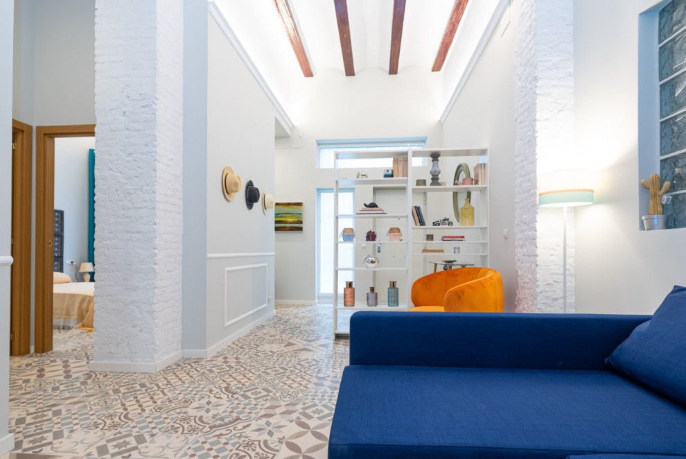 This is an example of a mid-sized mediterranean open concept family room in Valencia with white walls, ceramic floors, a wall-mounted tv, multi-coloured floor and exposed beam.