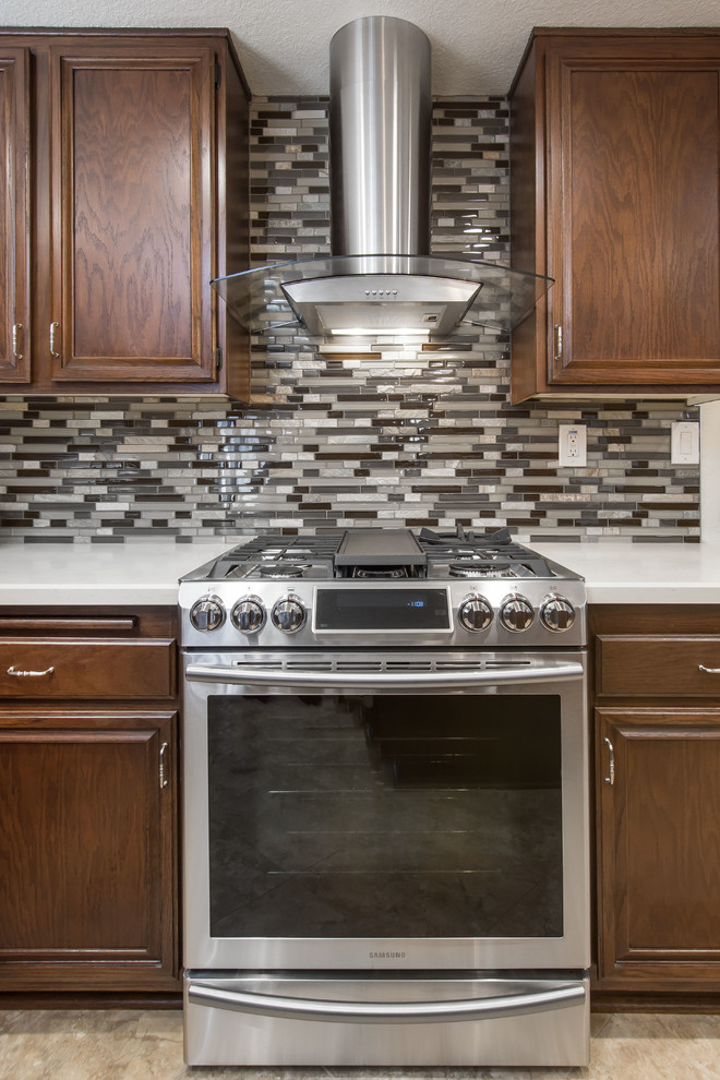 Example of a large transitional u-shaped cement tile floor and beige floor eat-in kitchen design in Los Angeles with a farmhouse sink, raised-panel cabinets, dark wood cabinets, quartz countertops, multicolored backsplash, glass tile backsplash, stainless steel appliances, an island and white countertops