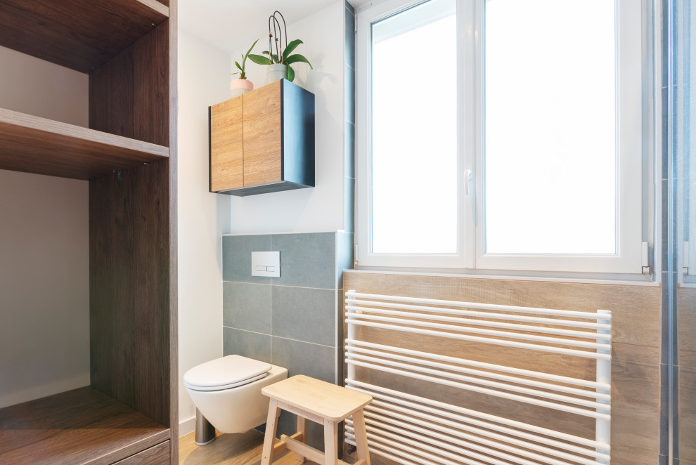Modelo de cuarto de baño principal, largo y estrecho, único, flotante y gris y negro contemporáneo de tamaño medio con puertas de armario de madera clara, ducha a ras de suelo, sanitario de pared, imitación madera, imitación a madera, encimera de laminado y encimeras negras