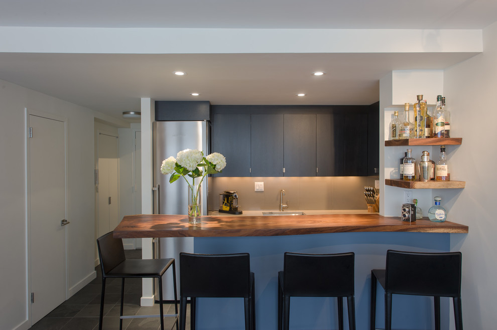 Design ideas for a mid-sized contemporary single-wall eat-in kitchen in New York with an undermount sink, flat-panel cabinets, dark wood cabinets, wood benchtops, brown splashback, stainless steel appliances, a peninsula, slate floors and grey floor.