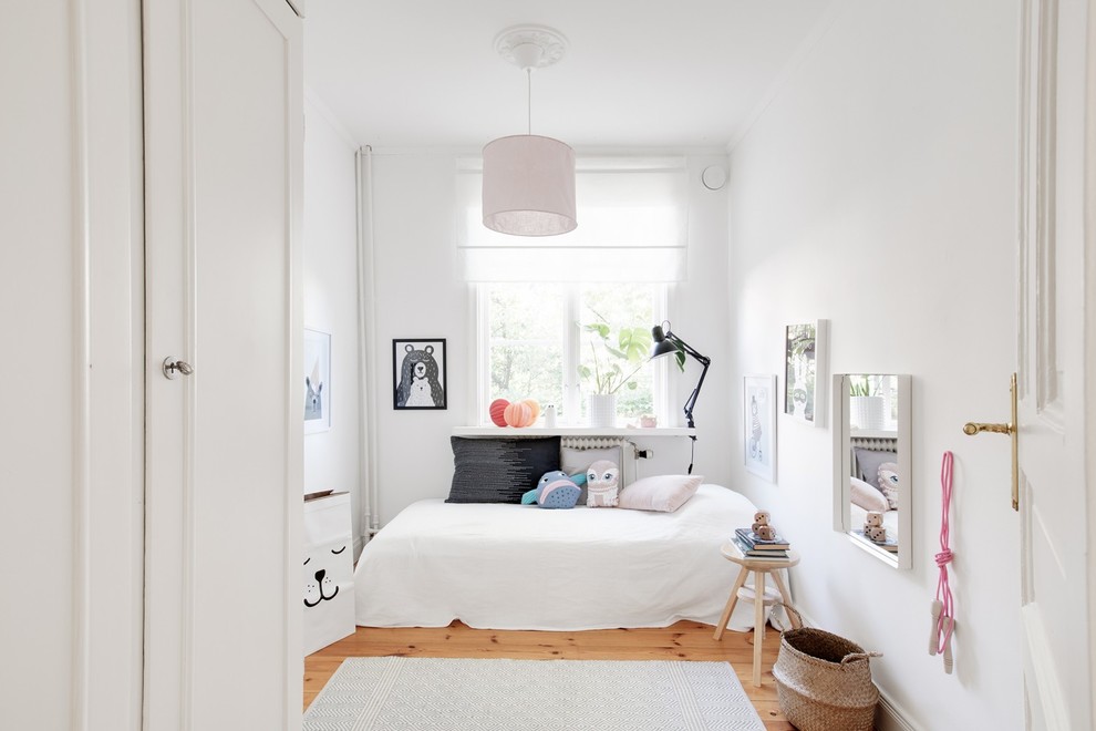 Photo of a small scandinavian kids' bedroom for kids 4-10 years old and girls with white walls, light hardwood floors and beige floor.