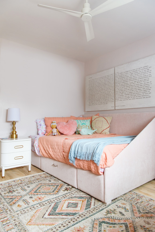 Photo of a transitional kids' bedroom for kids 4-10 years old and girls in San Diego with pink walls, light hardwood floors and beige floor.
