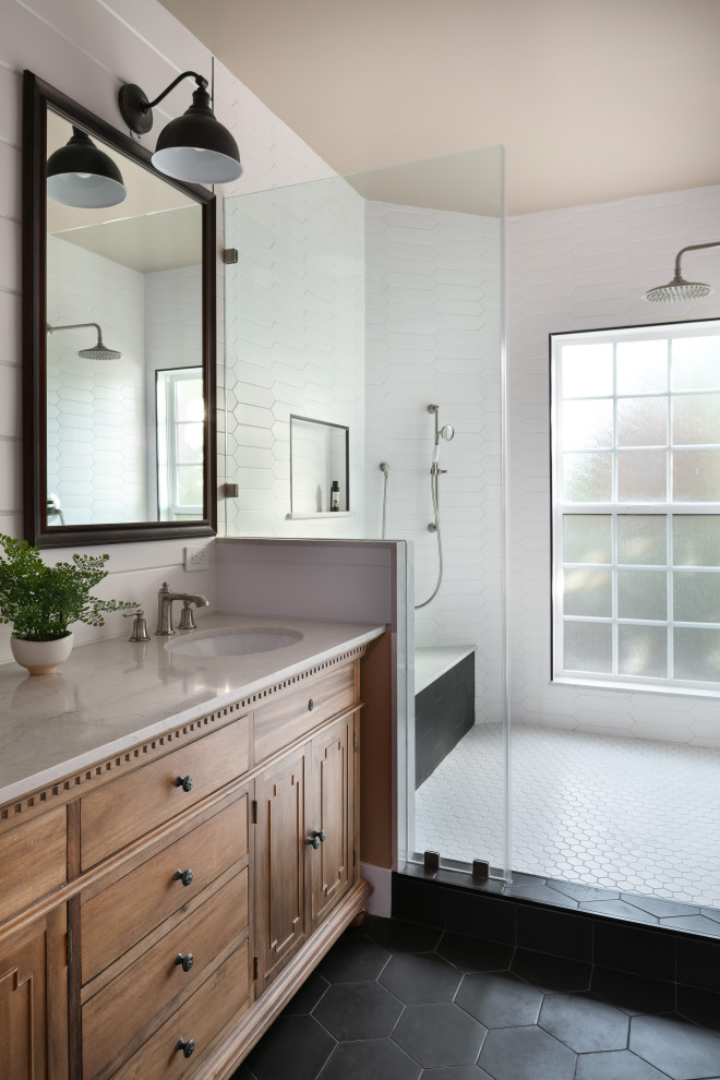 This is an example of a large transitional master bathroom in Los Angeles with furniture-like cabinets, dark wood cabinets, a double shower, a one-piece toilet, white tile, subway tile, white walls, ceramic floors, an undermount sink, marble benchtops, black floor, beige benchtops, a shower seat, a double vanity, a freestanding vanity, planked wall panelling and a hinged shower door.
