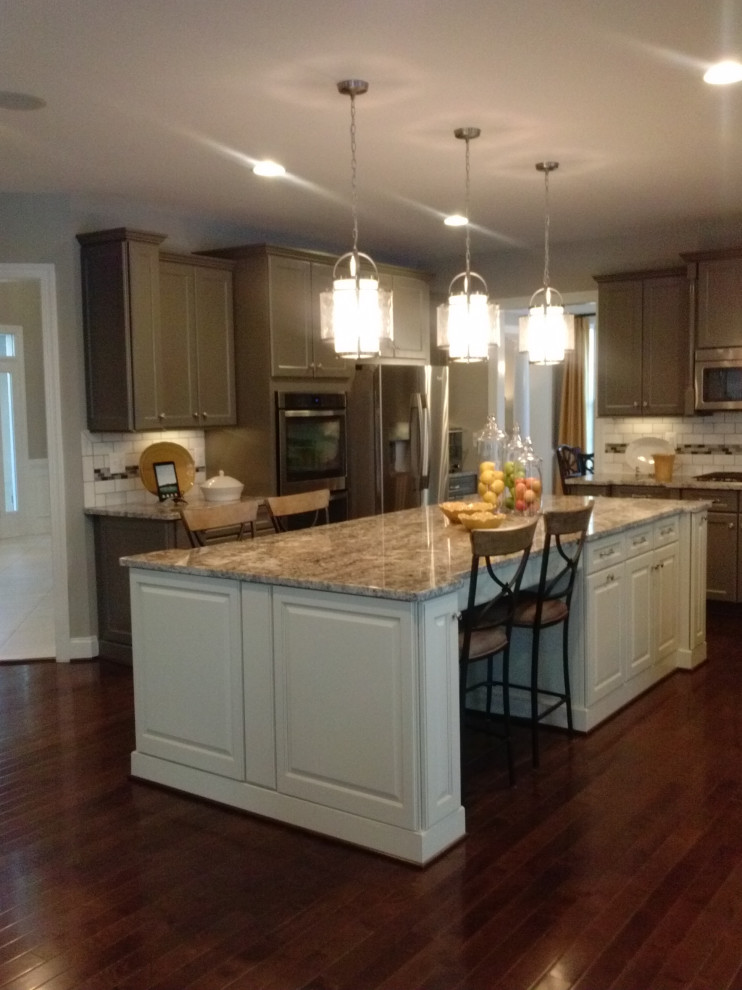 Example of a transitional l-shaped medium tone wood floor and red floor eat-in kitchen design with an undermount sink, raised-panel cabinets, gray cabinets, granite countertops, multicolored backsplash, subway tile backsplash, stainless steel appliances and multicolored countertops