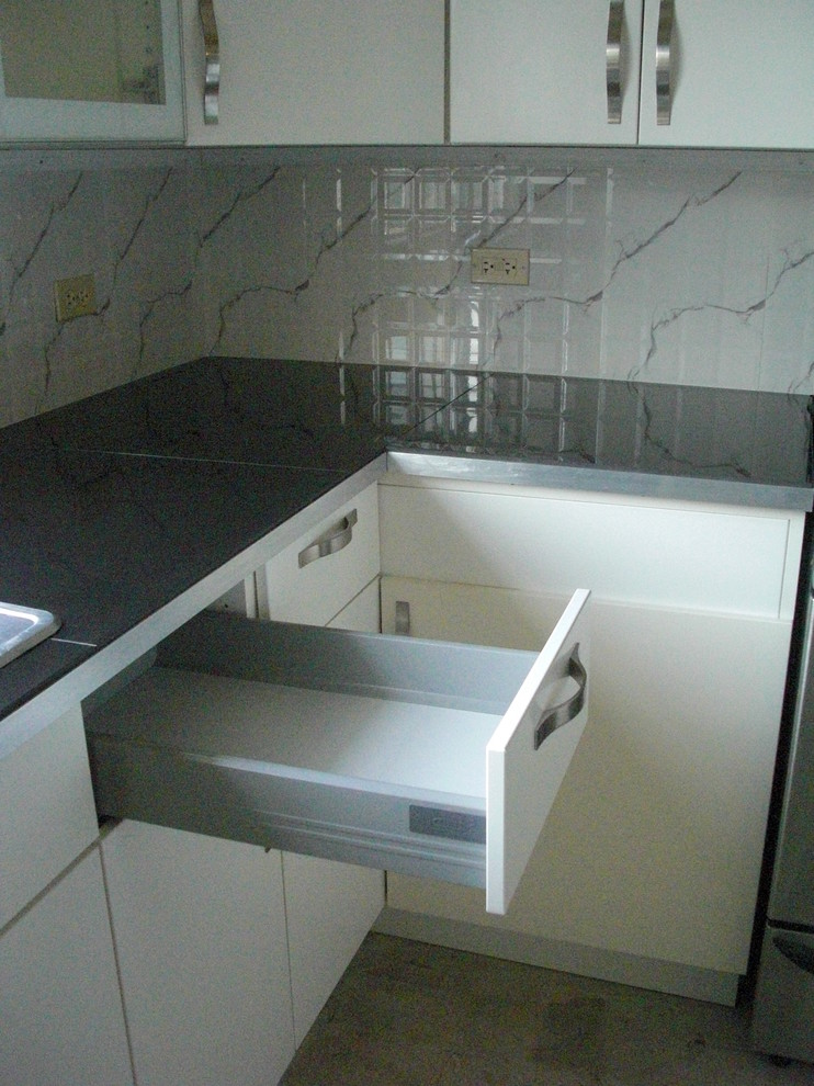 Example of a mid-sized trendy u-shaped kitchen pantry design with a double-bowl sink, flat-panel cabinets, white cabinets, quartz countertops, white backsplash, ceramic backsplash, stainless steel appliances and no island