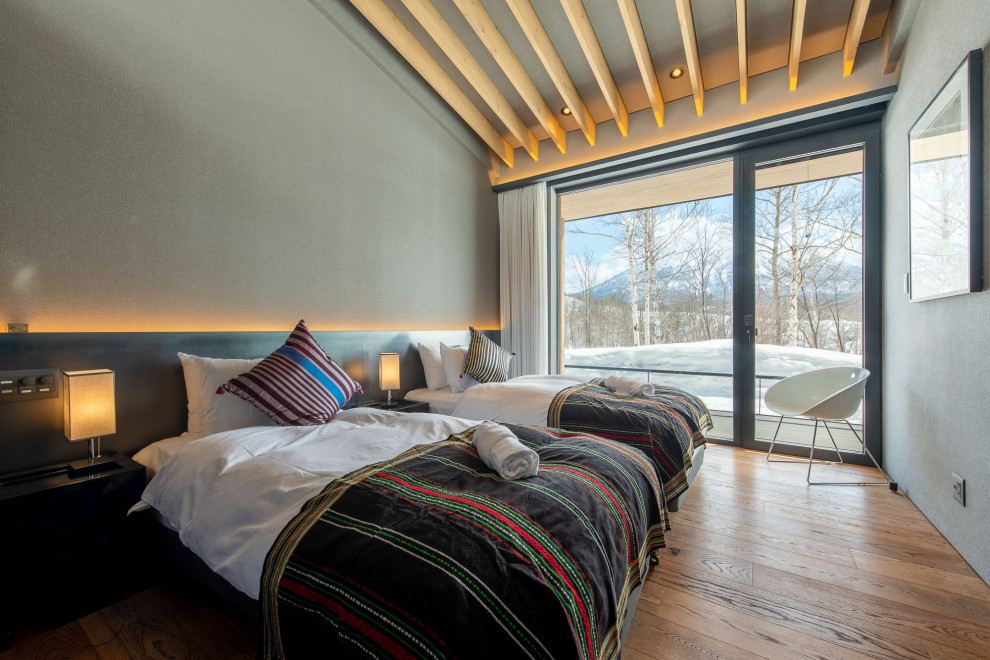 На фото: большая спальня на антресоли в стиле рустика с серыми стенами, полом из фанеры, бежевым полом, балками на потолке и обоями на стенах без камина