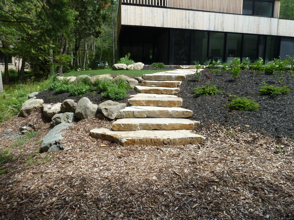 Design ideas for a large contemporary full sun side yard stone landscaping in Montreal.