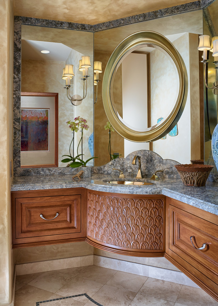 Tropical bathroom in Los Angeles with an undermount sink, medium wood cabinets, beige tile, granite benchtops, stone tile and recessed-panel cabinets.