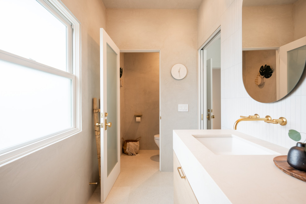 Minimalistisk inredning av ett mellanstort beige beige en-suite badrum, med släta luckor, en dusch i en alkov, en vägghängd toalettstol, beige kakel, kakelplattor, beige väggar, klinkergolv i keramik, ett undermonterad handfat, bänkskiva i kvarts, beiget golv och dusch med gångjärnsdörr