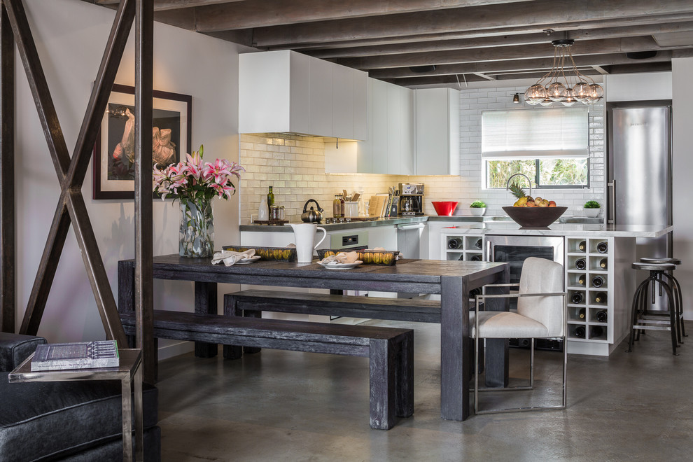 Contemporary l-shaped eat-in kitchen in Los Angeles with flat-panel cabinets, white cabinets, white splashback, subway tile splashback and stainless steel appliances.