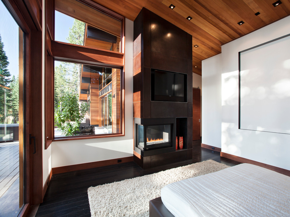 Photo of a large modern master bedroom in San Francisco with white walls, painted wood floors, a corner fireplace and a metal fireplace surround.