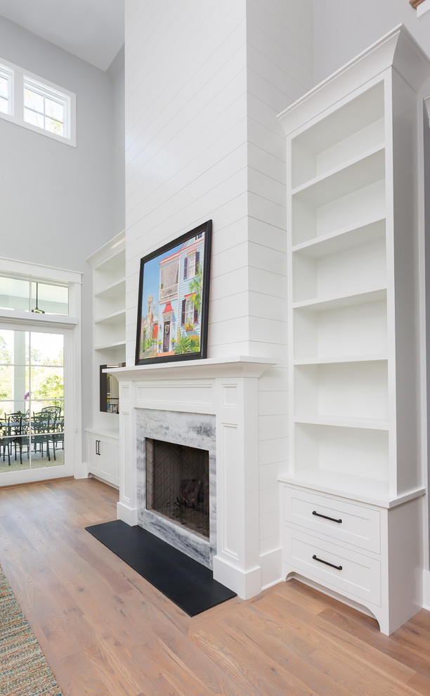 Photo of a mid-sized beach style open concept family room in Charleston with a home bar, grey walls, medium hardwood floors, a standard fireplace, a stone fireplace surround, a built-in media wall and brown floor.