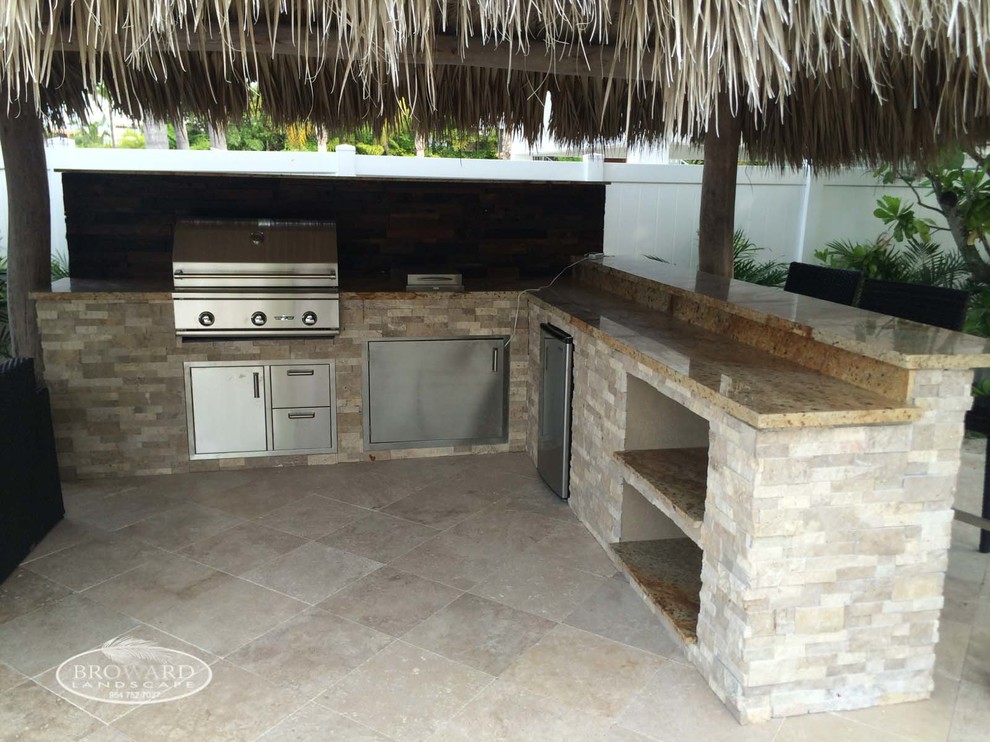Inspiration for a large beach style backyard patio in Miami with an outdoor kitchen and natural stone pavers.