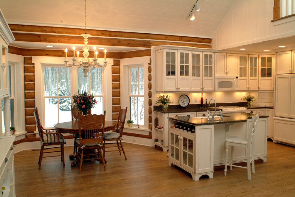 Country l-shaped eat-in kitchen in Grand Rapids with glass-front cabinets, white cabinets, white splashback and panelled appliances.