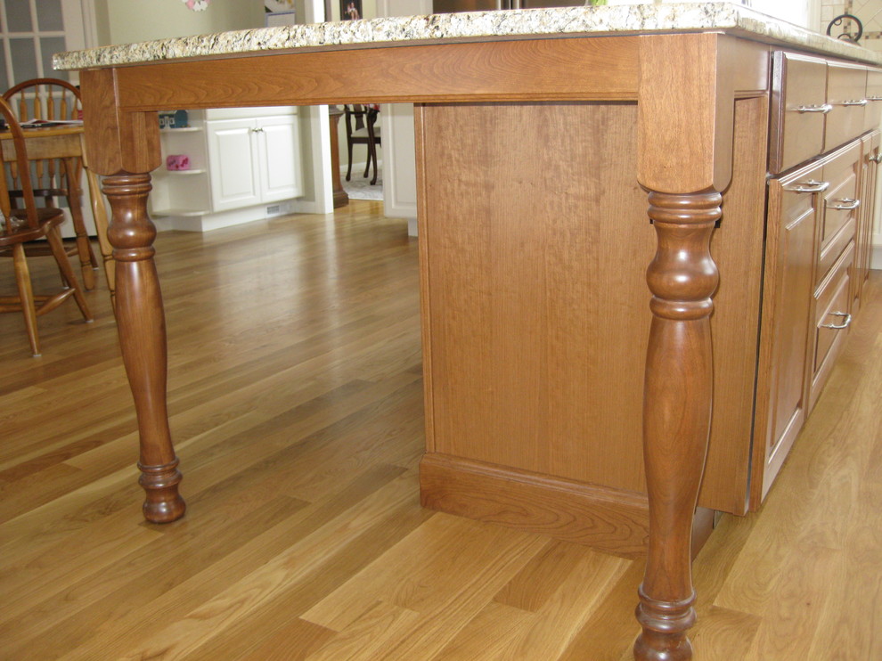 Inspiration for a transitional u-shaped medium tone wood floor eat-in kitchen remodel in Boston with an undermount sink, raised-panel cabinets, white cabinets, granite countertops, white backsplash, ceramic backsplash, stainless steel appliances, an island and beige countertops