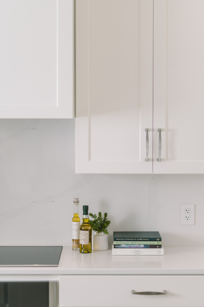 Inspiration for a large transitional l-shaped laminate floor and brown floor eat-in kitchen remodel with an undermount sink, shaker cabinets, white cabinets, quartz countertops, white backsplash, quartz backsplash, stainless steel appliances, an island and white countertops