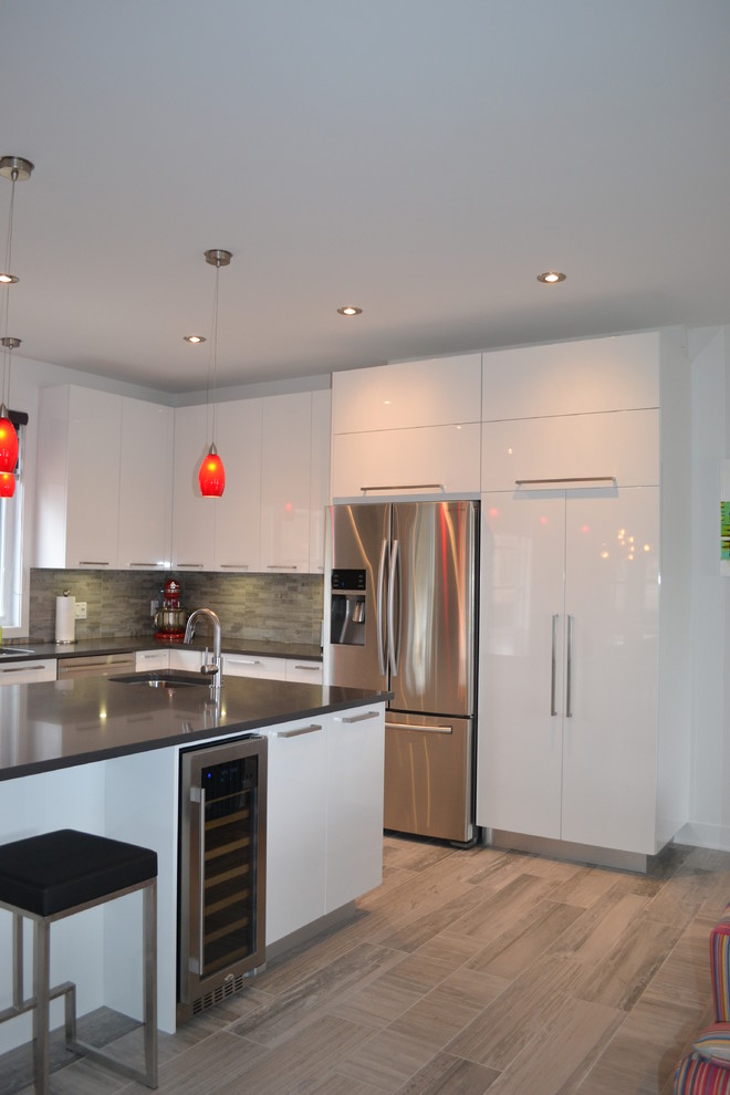 Design ideas for a large modern l-shaped open plan kitchen in Montreal with an undermount sink, flat-panel cabinets, white cabinets, granite benchtops, grey splashback, ceramic splashback, stainless steel appliances, vinyl floors, with island, beige floor and grey benchtop.
