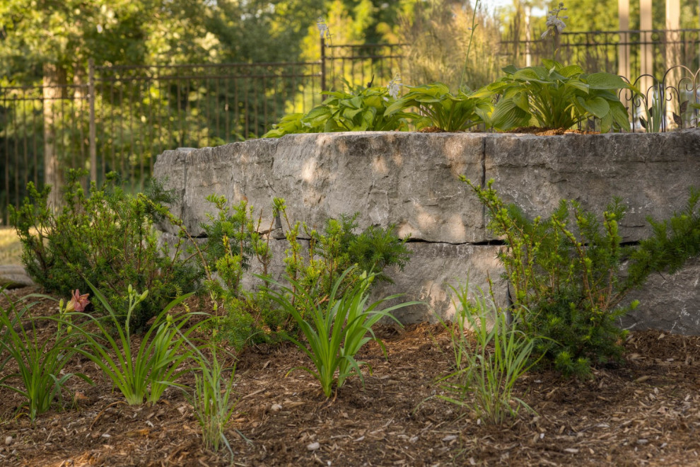 Photo of a mid-sized transitional shade backyard stone retaining wall landscape in Toronto for summer.