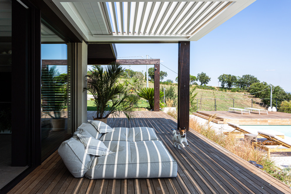 Design ideas for a mid-sized contemporary front yard verandah in Bologna with decking and a pergola.