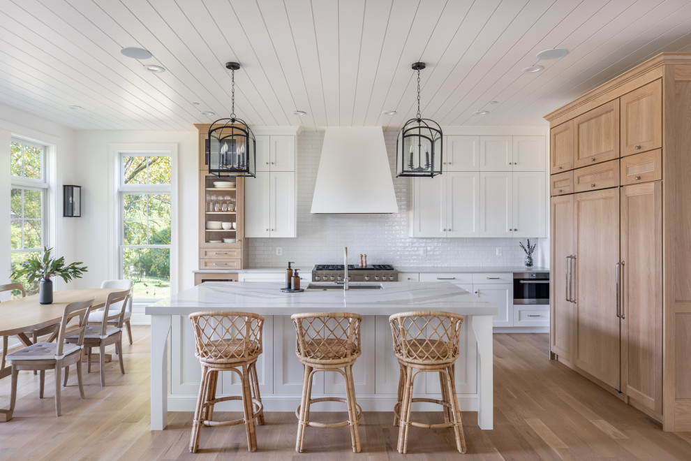Inspiration for a transitional l-shaped kitchen in DC Metro with an undermount sink, recessed-panel cabinets, white cabinets, white splashback, medium hardwood floors, with island, brown floor, white benchtop and timber.