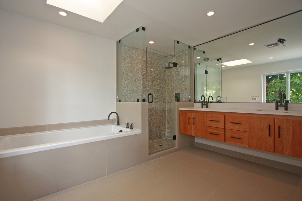 This is an example of a contemporary bathroom in Miami with flat-panel cabinets, medium wood cabinets, a corner shower, beige tile and pebble tile.