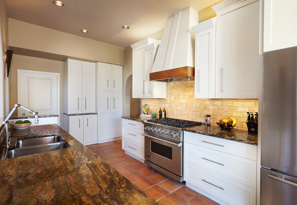 Mid-sized transitional galley terra-cotta tile kitchen photo in Phoenix with a double-bowl sink, shaker cabinets, white cabinets, granite countertops, beige backsplash, stone tile backsplash and stainless steel appliances