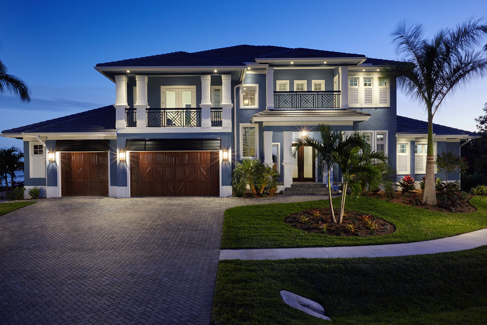 Large beach style two-storey stucco blue exterior in Miami with a gable roof.