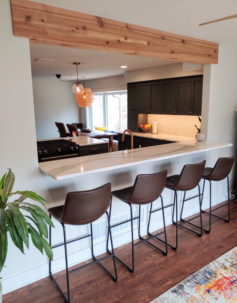 Eat-in kitchen - mid-sized transitional l-shaped dark wood floor eat-in kitchen idea with a farmhouse sink, recessed-panel cabinets, green cabinets, quartz countertops, white backsplash, black appliances, an island and white countertops
