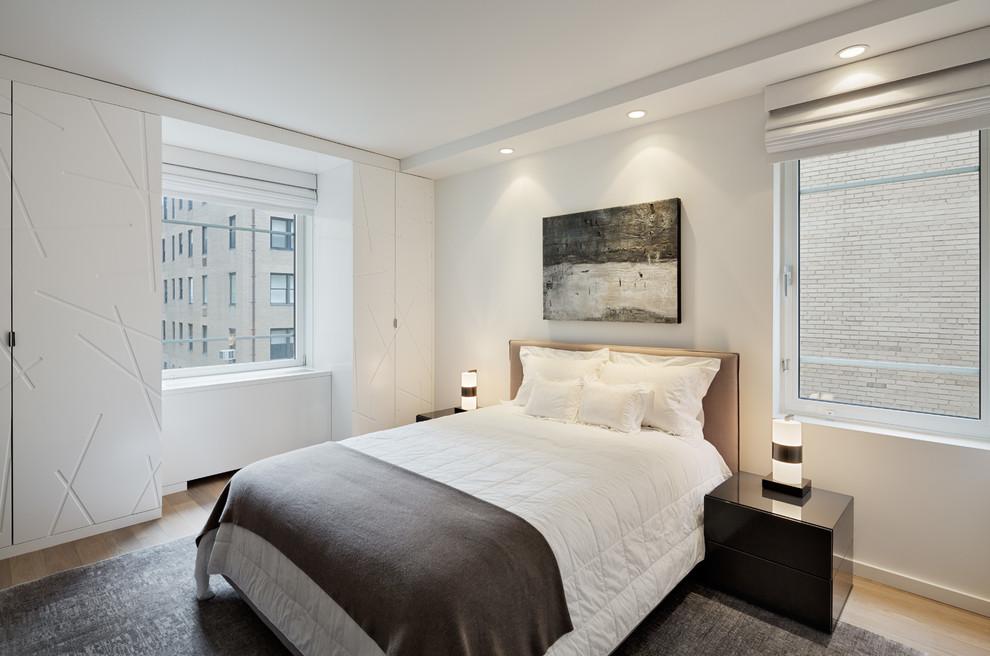 This is an example of a mid-sized contemporary master bedroom in New York with white walls, light hardwood floors and no fireplace.