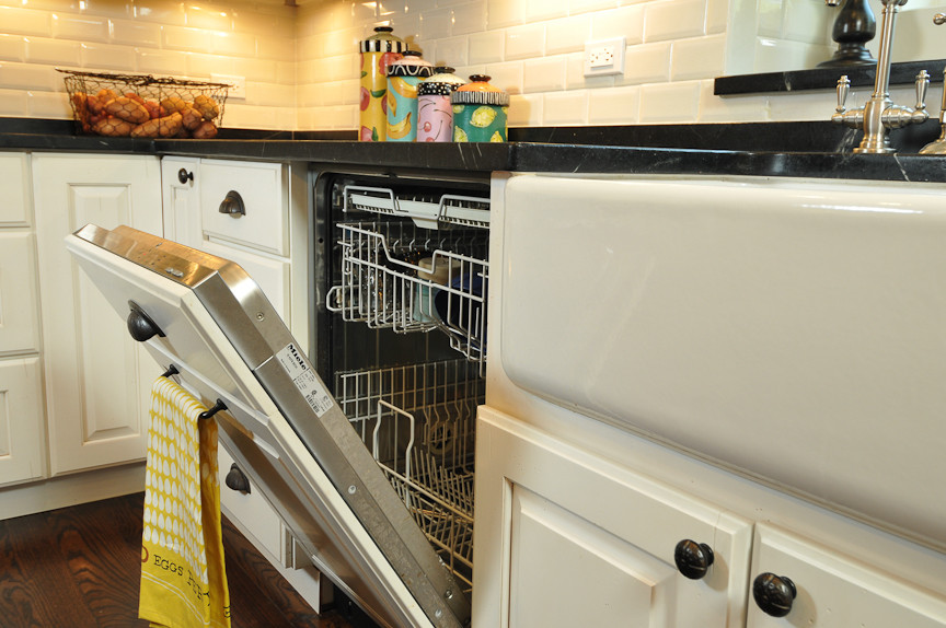 Inspiration for a rustic l-shaped eat-in kitchen remodel in Chicago with a farmhouse sink, raised-panel cabinets, white cabinets, soapstone countertops, white backsplash, subway tile backsplash and paneled appliances