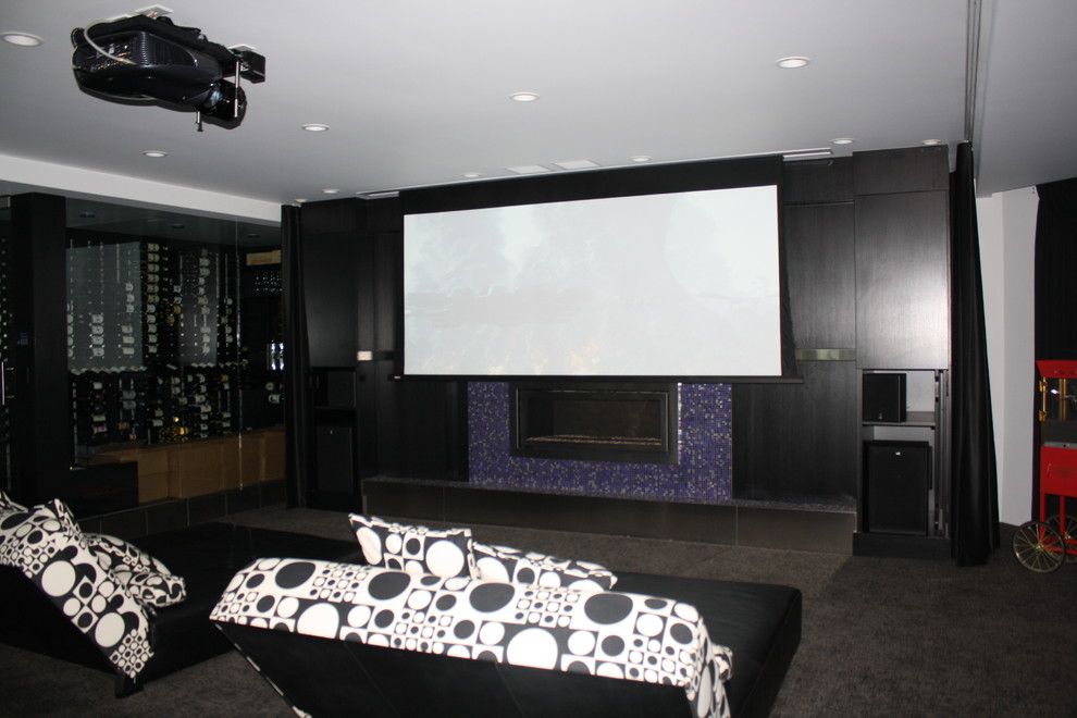 Inspiration for a large modern enclosed home theatre in Chicago with a projector screen, black walls and carpet.