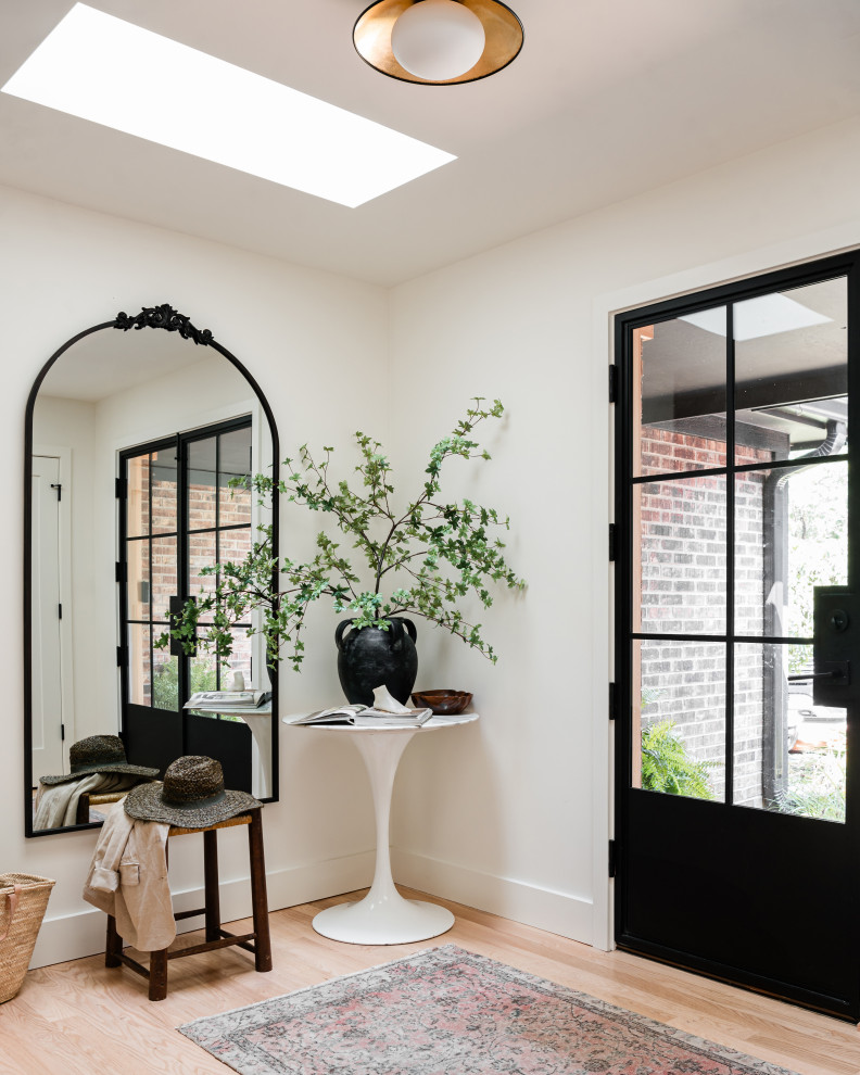 Example of a mid-sized transitional light wood floor front door design in Chicago with white walls and a black front door