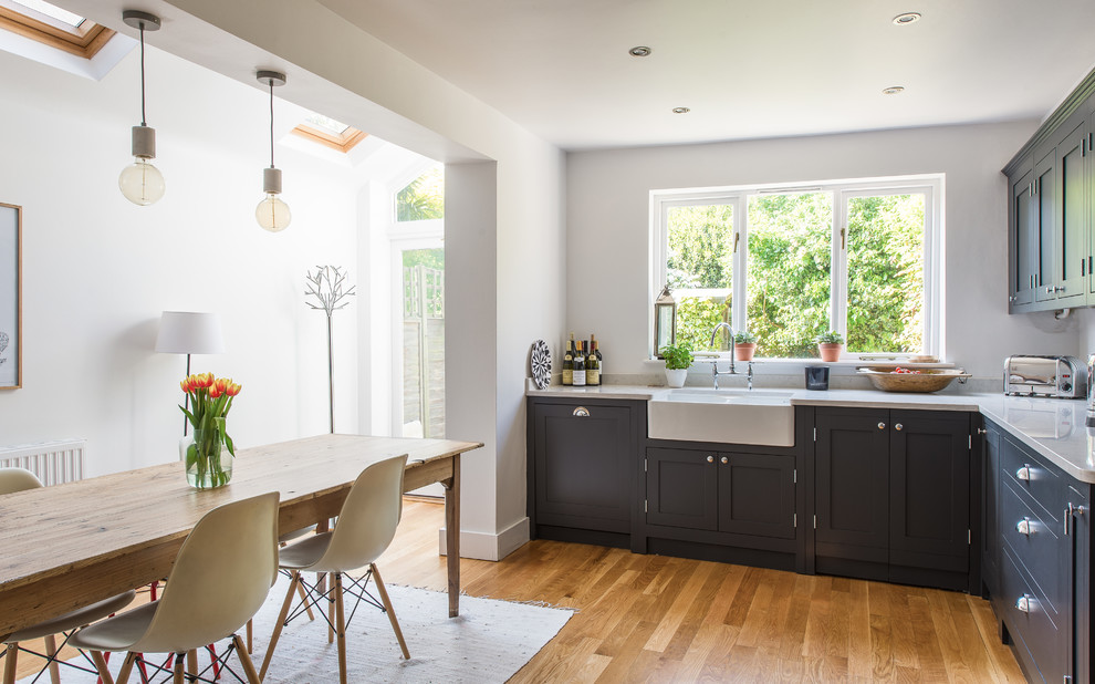 Inspiration for a small country eat-in kitchen in London with shaker cabinets, dark wood cabinets and light hardwood floors.