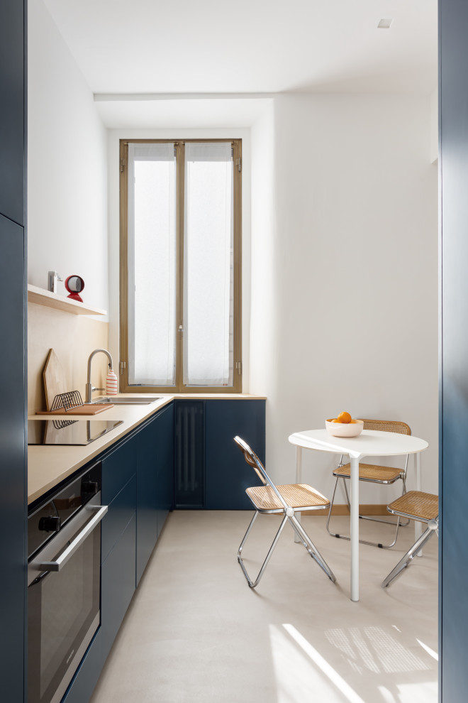 На фото: угловая кухня-гостиная среднего размера в современном стиле с плоскими фасадами, синими фасадами, столешницей из бетона, желтым фартуком, бетонным полом, серым полом и желтой столешницей без острова с