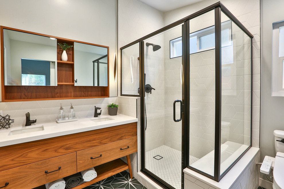 Medium sized retro ensuite bathroom in Chicago with flat-panel cabinets, medium wood cabinets, a corner shower, a two-piece toilet, white tiles, grey walls, a submerged sink, a hinged door, white worktops, a shower bench, double sinks and a freestanding vanity unit.