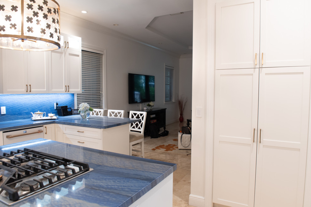 Mid-sized traditional u-shaped eat-in kitchen in Miami with an undermount sink, shaker cabinets, white cabinets, blue splashback, white appliances, with island and blue benchtop.