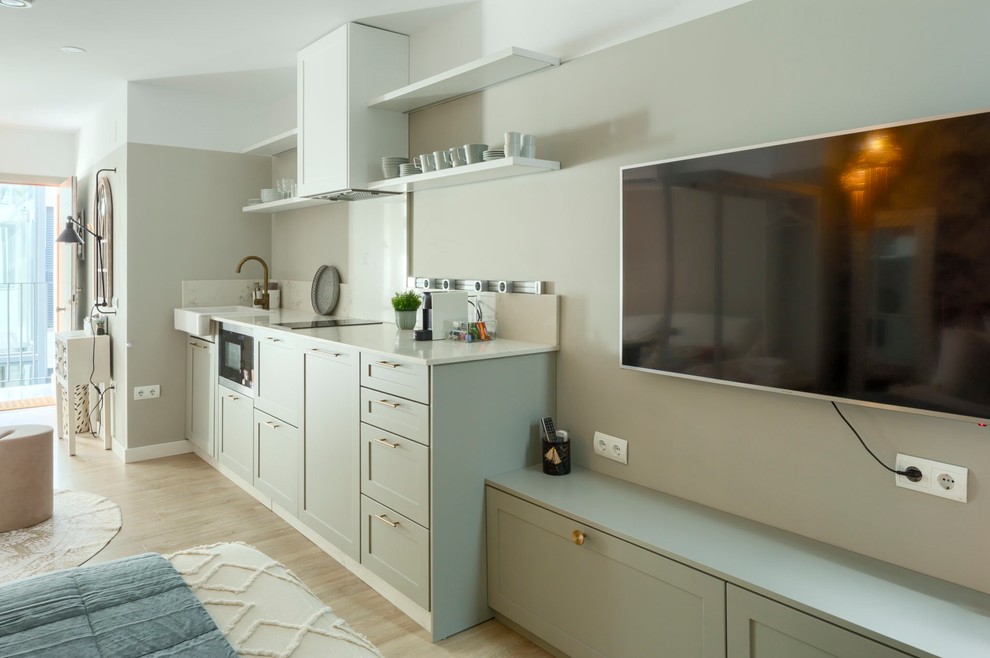 This is an example of a small modern single-wall open plan kitchen in Malaga with a single-bowl sink, raised-panel cabinets, green cabinets, quartz benchtops, white splashback, panelled appliances, porcelain floors, with island, brown floor and white benchtop.