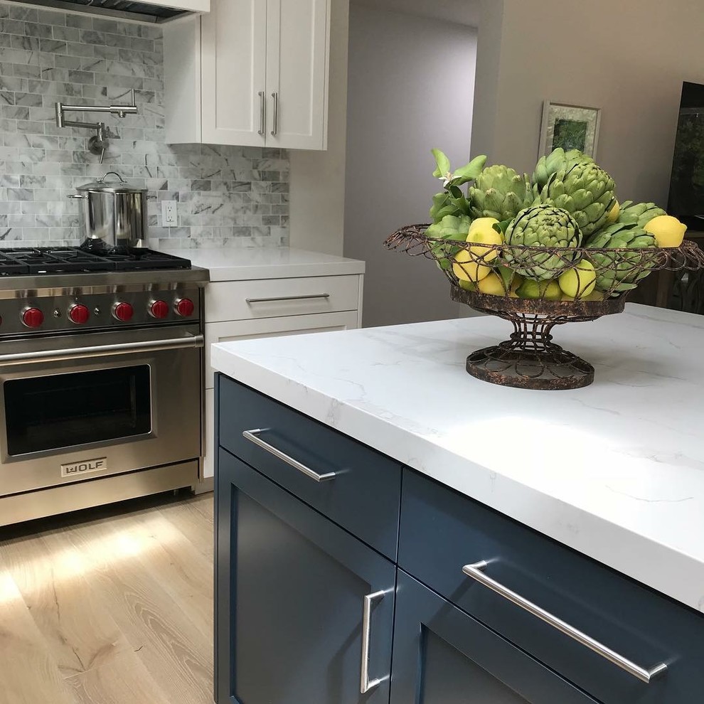 Mid-sized country kitchen in San Francisco with shaker cabinets, white cabinets, quartz benchtops, grey splashback, stone tile splashback, stainless steel appliances, light hardwood floors, with island, beige floor and white benchtop.