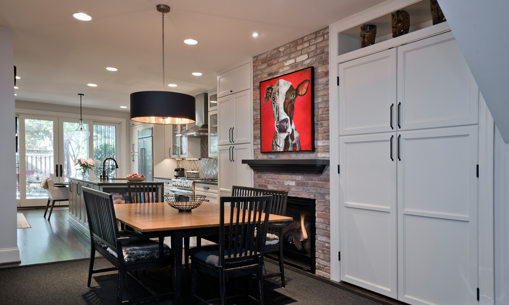 This is an example of a mid-sized contemporary kitchen/dining combo in DC Metro with grey walls, dark hardwood floors, a standard fireplace, a brick fireplace surround, brown floor and brick walls.