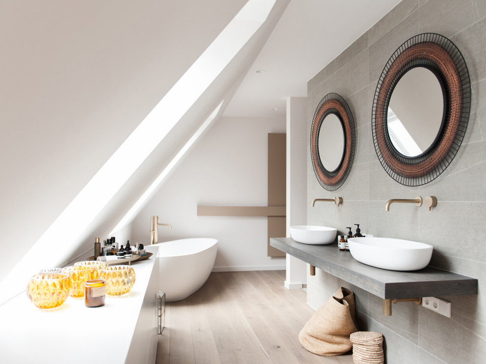 Стильный дизайн: ванная комната в современном стиле с отдельно стоящей ванной, серой плиткой, белыми стенами, светлым паркетным полом, настольной раковиной, бежевым полом и серой столешницей - последний тренд