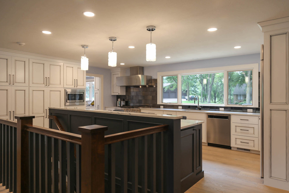 Example of a mid-sized transitional u-shaped light wood floor and beige floor eat-in kitchen design with an undermount sink, recessed-panel cabinets, white cabinets, quartzite countertops, black backsplash, porcelain backsplash, stainless steel appliances, an island and white countertops