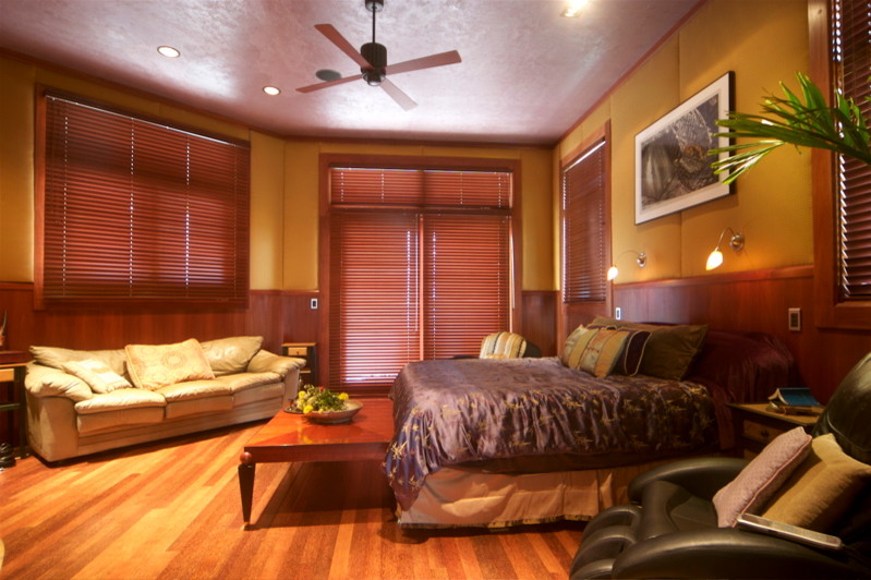 This is an example of a large arts and crafts master bedroom in Hawaii with multi-coloured walls and light hardwood floors.