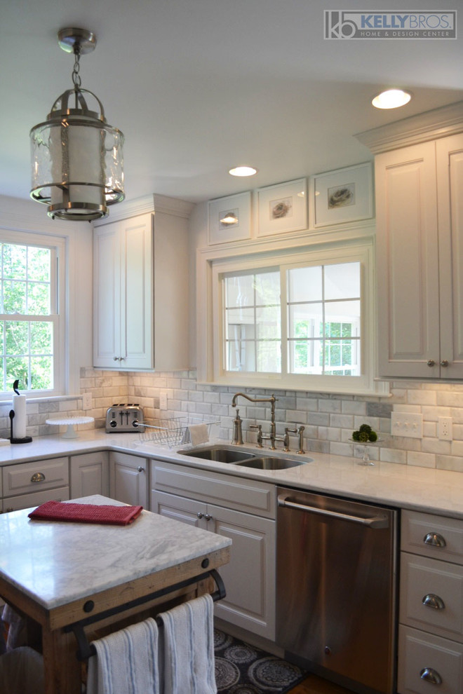Eat-in kitchen - mid-sized transitional u-shaped medium tone wood floor eat-in kitchen idea in Cincinnati with an undermount sink, raised-panel cabinets, white cabinets, quartz countertops, white backsplash, subway tile backsplash, stainless steel appliances, white walls and an island