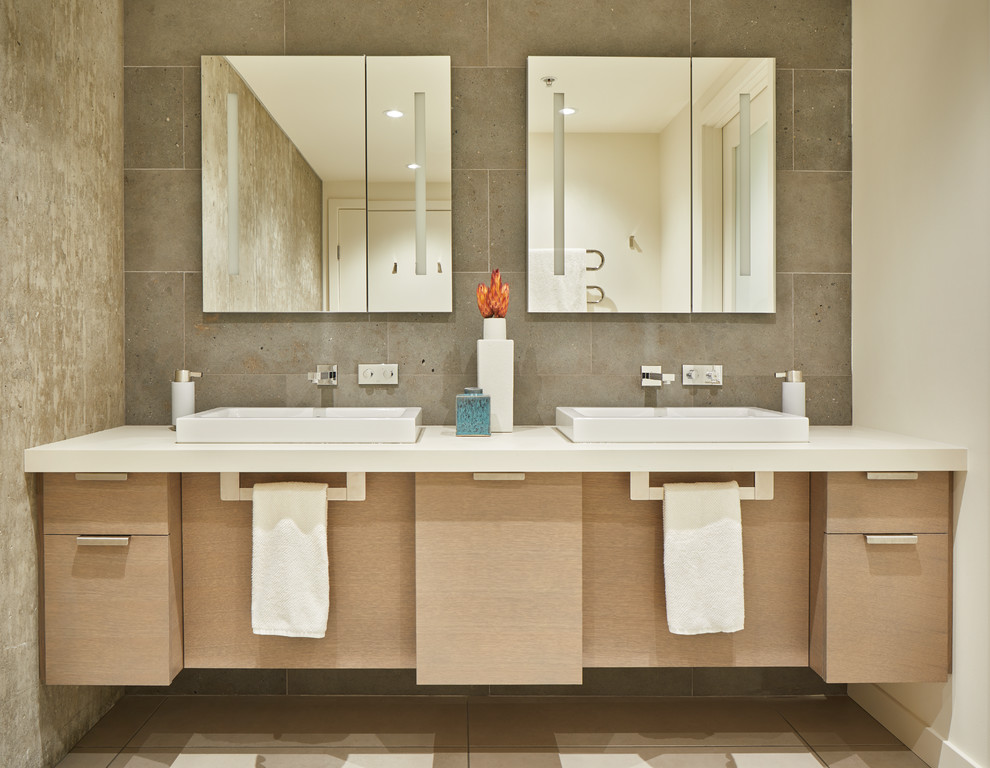 This is an example of a large contemporary master bathroom in Seattle with flat-panel cabinets, gray tile, limestone, ceramic floors, a vessel sink, engineered quartz benchtops, grey floor, light wood cabinets, white walls and white benchtops.
