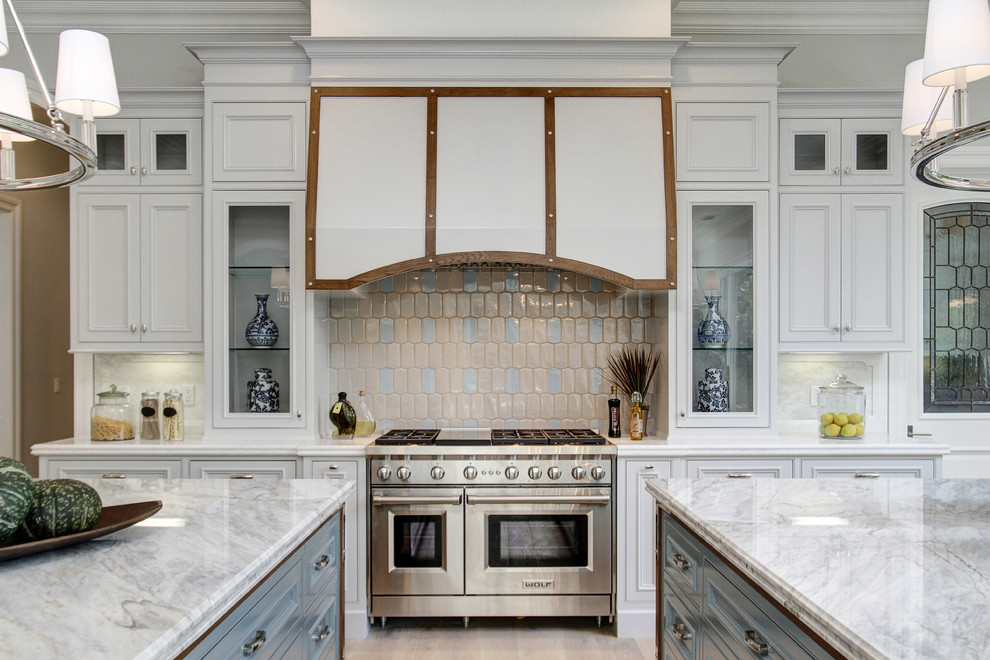 Photo of a traditional kitchen in Los Angeles with recessed-panel cabinets, white cabinets, multi-coloured splashback, stainless steel appliances and multiple islands.