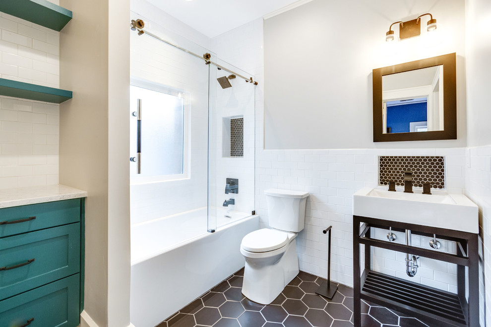 Inspiration for a small transitional kids bathroom in Birmingham with recessed-panel cabinets, turquoise cabinets, an alcove tub, a shower/bathtub combo, a two-piece toilet, white tile, subway tile, grey walls, porcelain floors, a console sink, engineered quartz benchtops, black floor, a sliding shower screen and white benchtops.